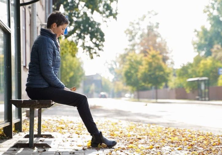 Woman waiting at bus stop after returning home after living years abroad