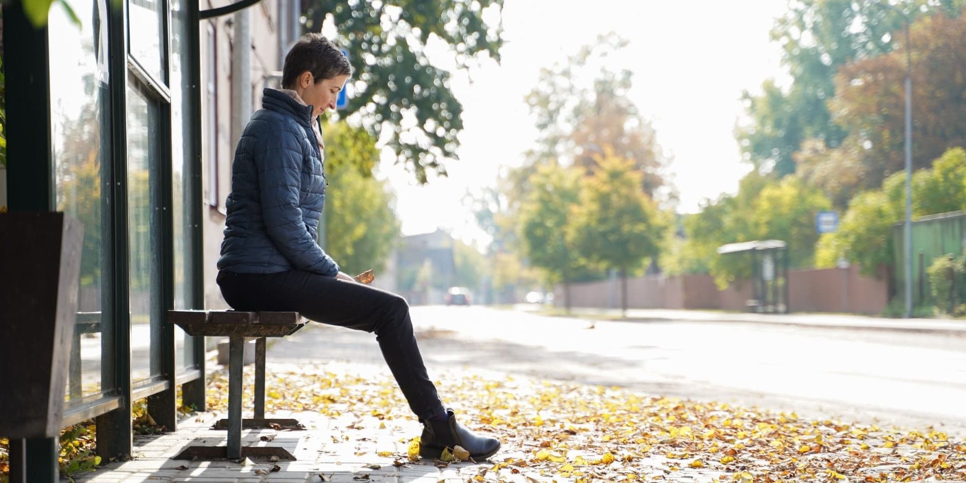 Woman waiting at bus stop after returning home after living years abroad